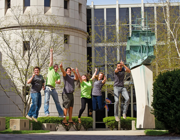 six diverse students jumping with their index fingers outstretched in a number one sign