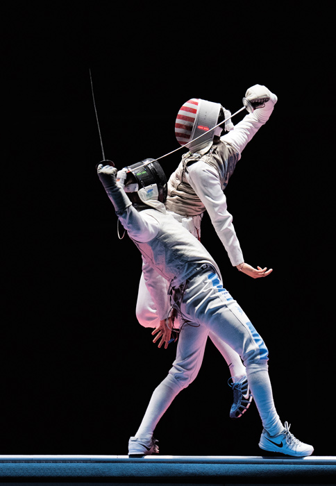 a fencer jumps in the air scoring on his opponent