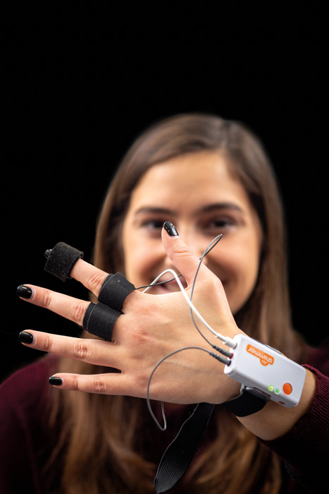 a woman wears a device on her hand that records her finger movements