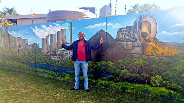 Takunda Ushe in front of a mural in Africa