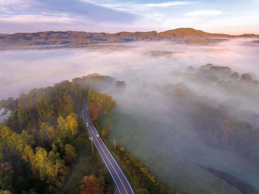 A highway disappears into mist and trees in the Appalachian mountains.