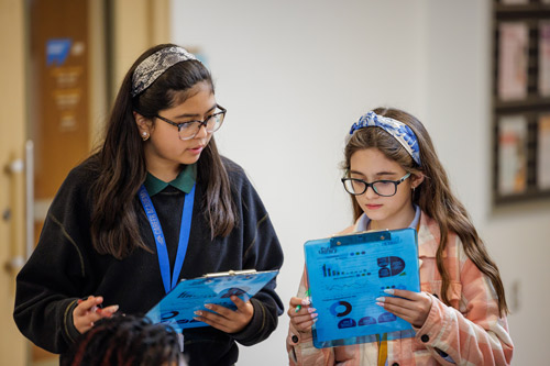 A Mendoza student talks with a middle schooler about an activity sheet