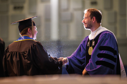 Dean Cremers shakes the hand of a graduate at Commencement